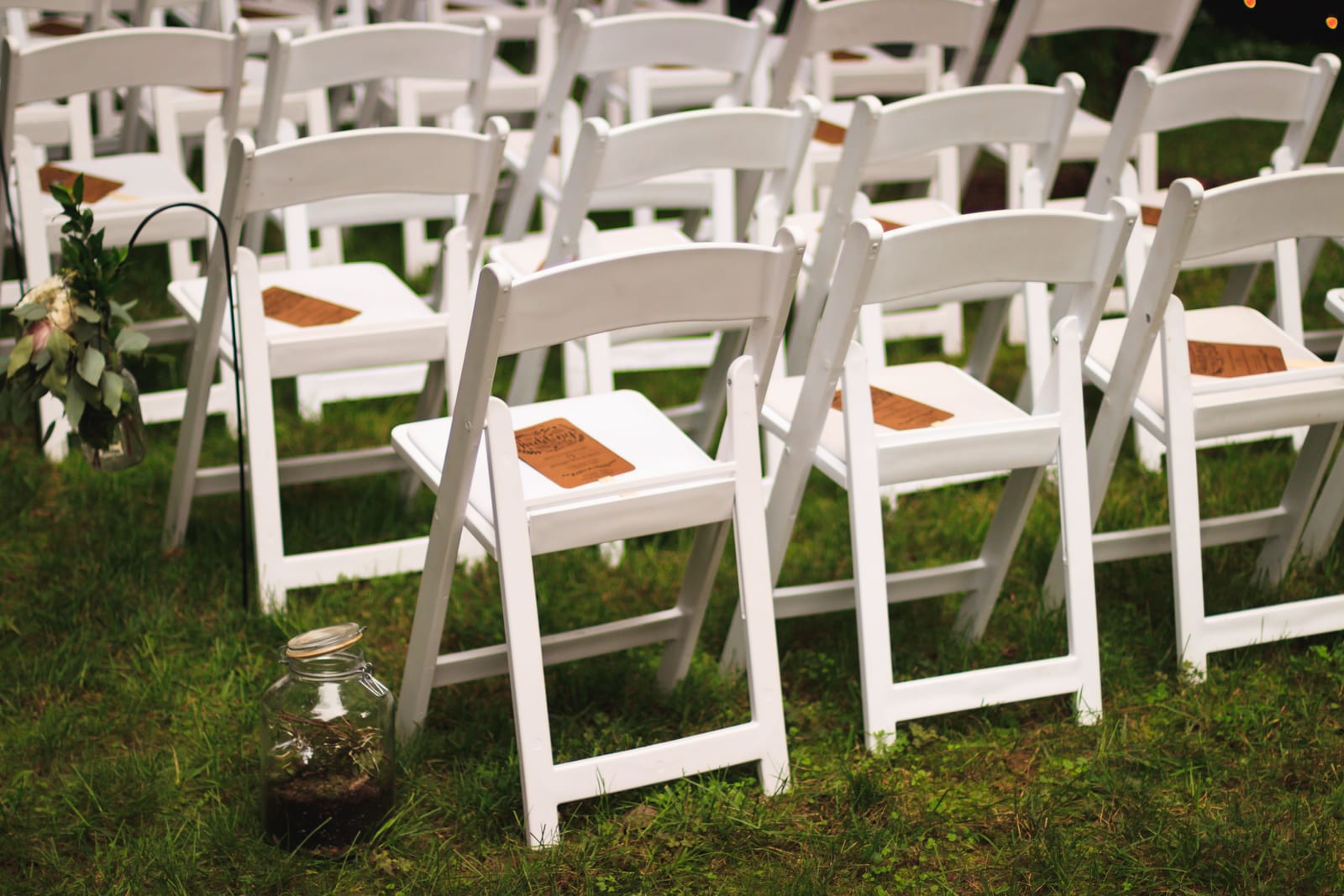 White ceremony chairs set out on a lawn.